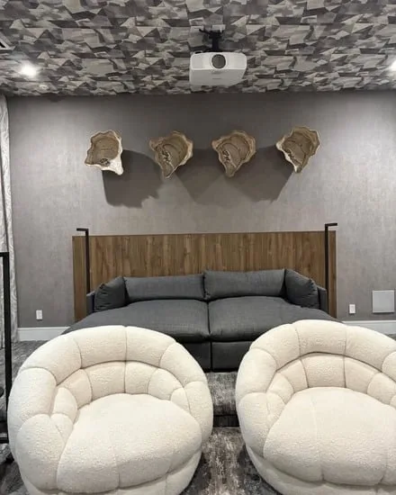 Bedroom moving and setup featuring a gray sofa and white accent chairs in a residential space.